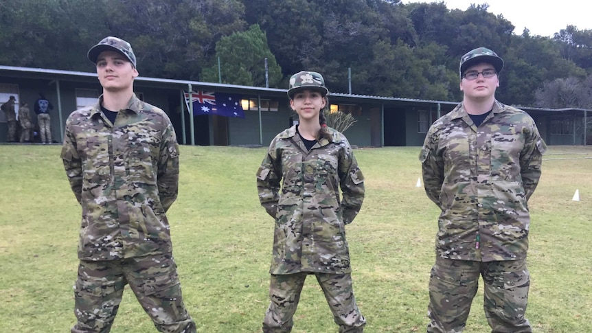 A group of teenagers stand in military fatigues at an army camp on the Gold Coast.