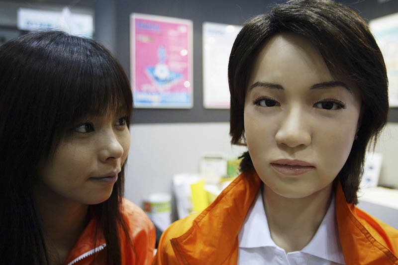 A woman looks at a female robot, or Actroid, at the 2003 International Robot Exhibition in Tokyo, Japan.