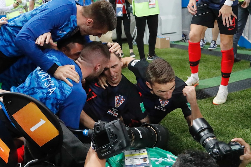 Croatia players pile on Mario Mandzukic and photographer
