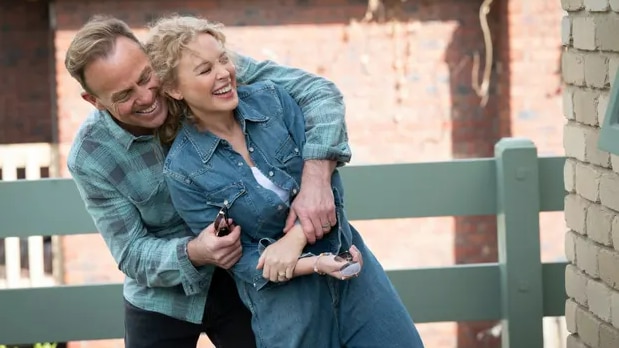 Kylie Minogue and Jason Donovan as Scott and Charlene in an embrace both wearing denim
