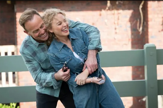 Kylie Minogue and Jason Donovan as Scott and Charlene in an embrace both wearing denim