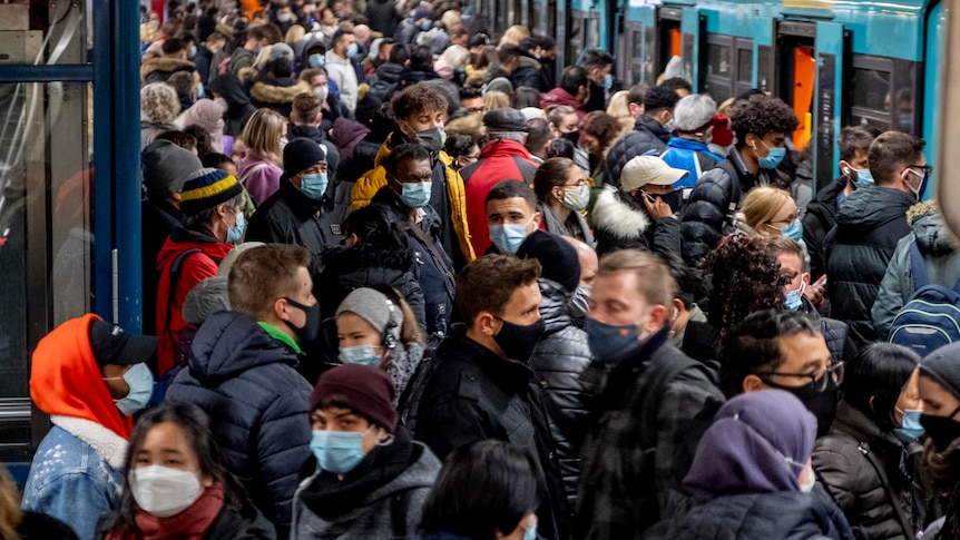 Las personas que llevan máscaras faciales permanecen cerca unas de otras mientras esperan el tren subterráneo en Frankfurt.
