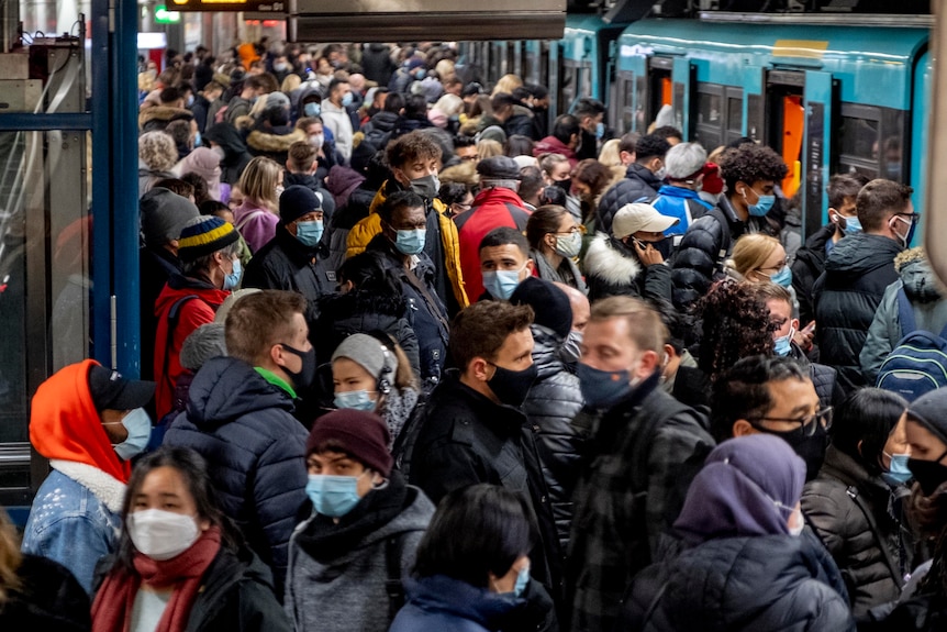 People with face masks stand close together while waiting for a subway train in Frankfurt.
