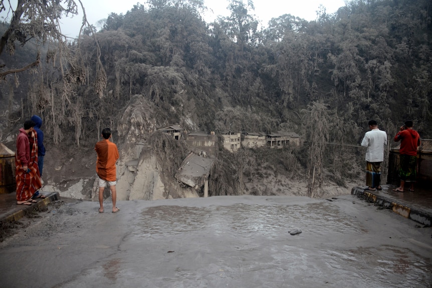 Villagers look at the broken bridge destroyed by lava flow