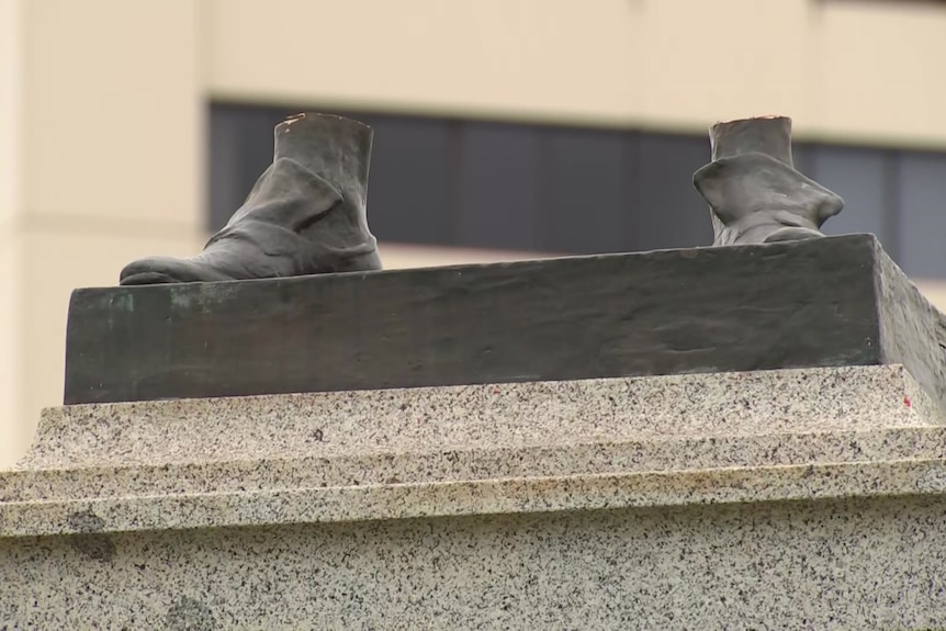 The bronze feet of a vandalised statue.