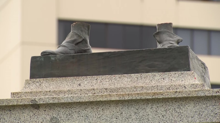 The bronze feet of a vandalised statue.