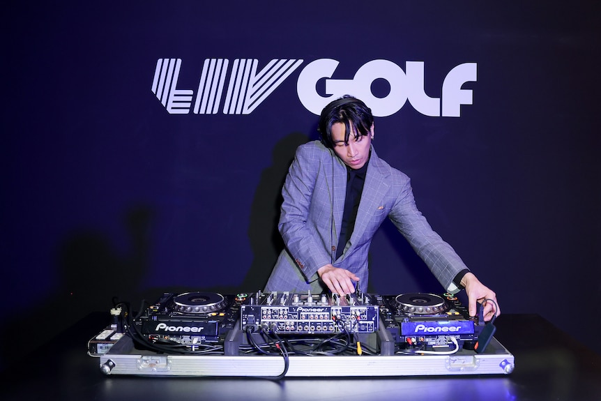 A DJ plays a set with a sign that reads LIV GOLF behind him
