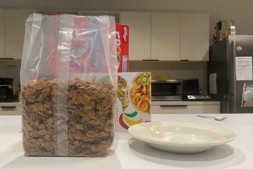 A bag of Sultana Bran sits outside its box on a kitchen counter with an empty white bowl beside it.