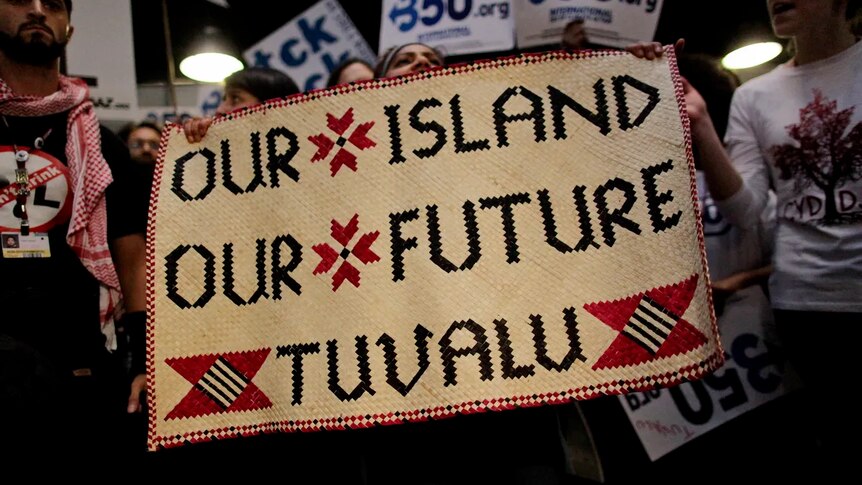 A hand woven banner held by activists that says - Our Island, Our Future, Tuvalu.