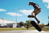 A teenager doing a jump on a skateboard.