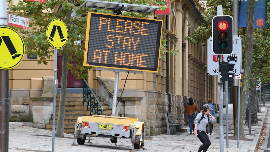 A digital sign on an inner city street corner in Sydney warns people to stay at home during the COVID lockdown.