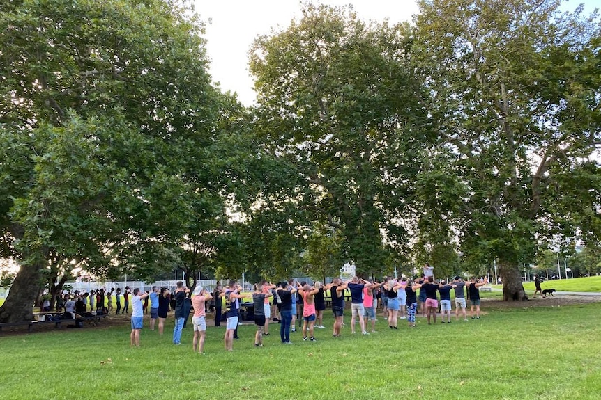 People rehearse synchronised dancing ahead of Mardi Gras in a park.