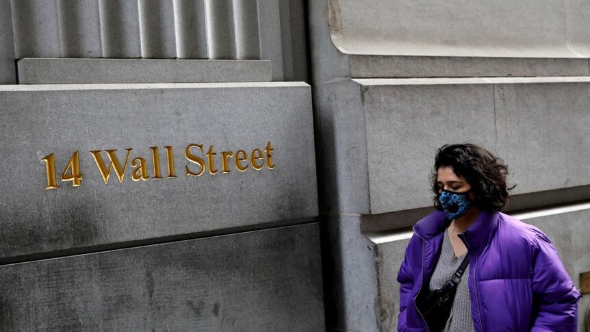A lady wearing a face mask walks along Wall Street in early March, during the coronavirus pandemic.