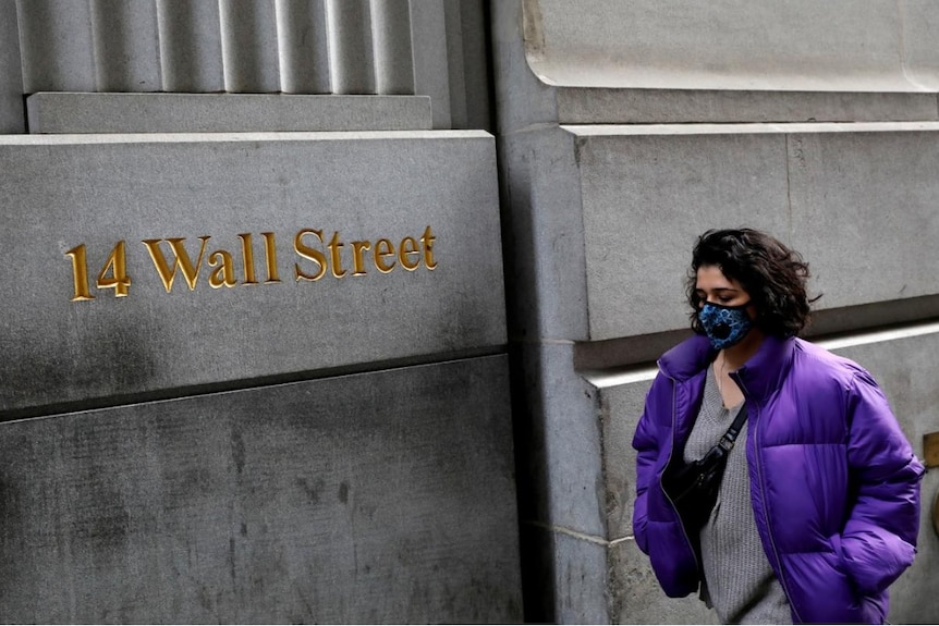 A lady wearing a face mask walks along Wall Street in early March, during the coronavirus pandemic.