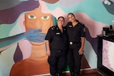Two Argentinian police women in the station with a brightly coloured wall