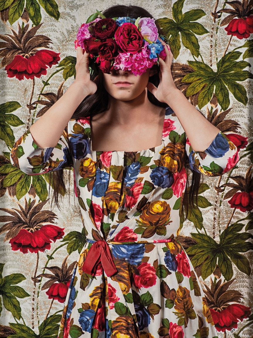 A photo of a women blindfolded in a floral dress and headband.