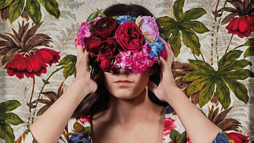 A photo of a women blindfolded in a floral dress and headband.