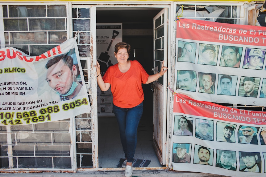 A woman stands in the doorway of an office covered in posters.