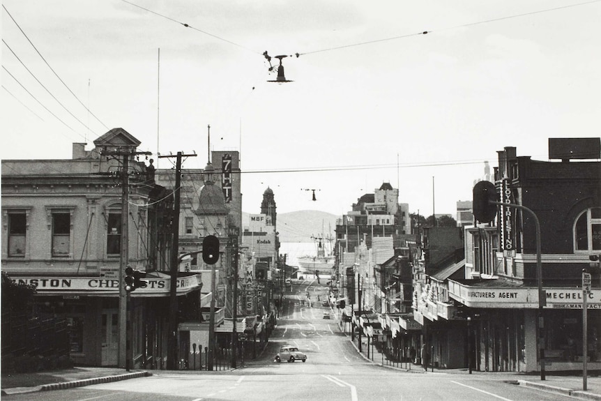A black and white photo ofHobart's Elizabeth Street facing the waterfront with shops signs of Crinston Chemists around 1960.