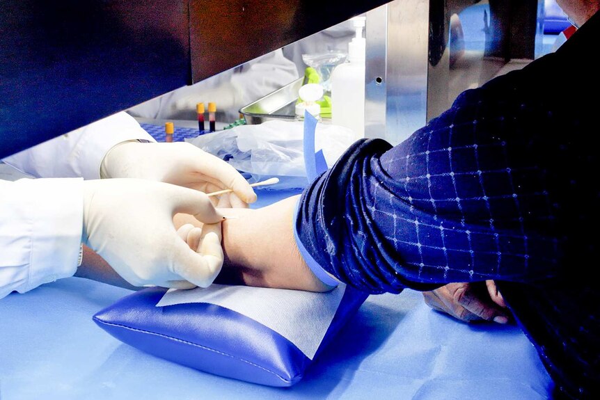 A close up shot of a doctor injecting something into a man's elbow crook