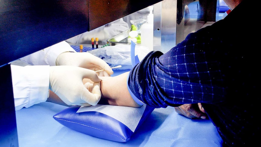 A close up shot of a doctor injecting something into a man's elbow crook