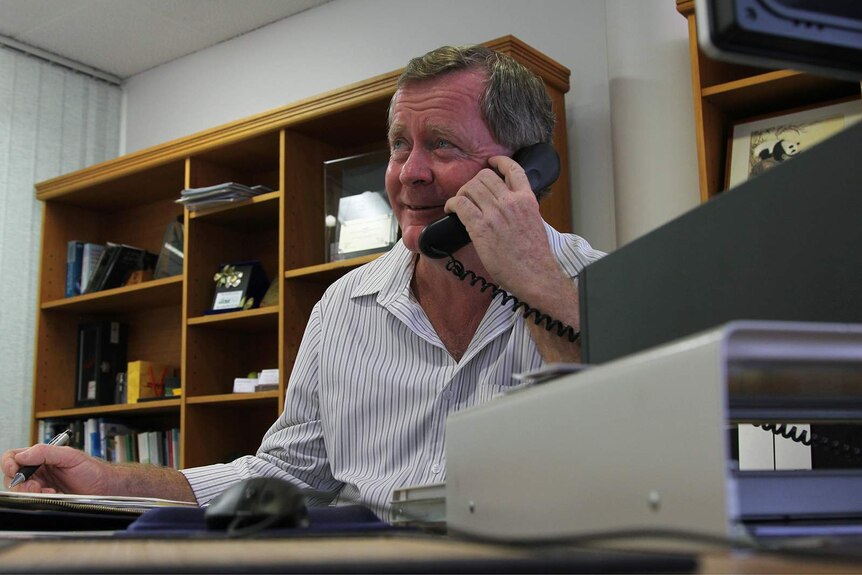 Acting Chamber of Commerce CEO Brian O'Gallagher sits at an office desk talking on the phone.
