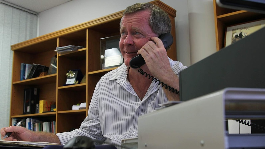 Acting Chamber of Commerce CEO Brian O'Gallagher sits at an office desk talking on the phone.