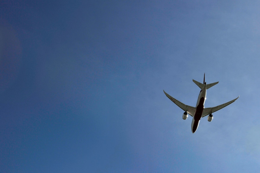 a plane departing sydney international airport flying on blue skies