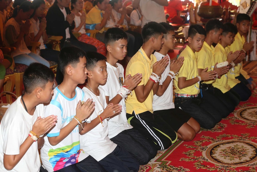 Members of Thai soccer team lined up kneeling and praying