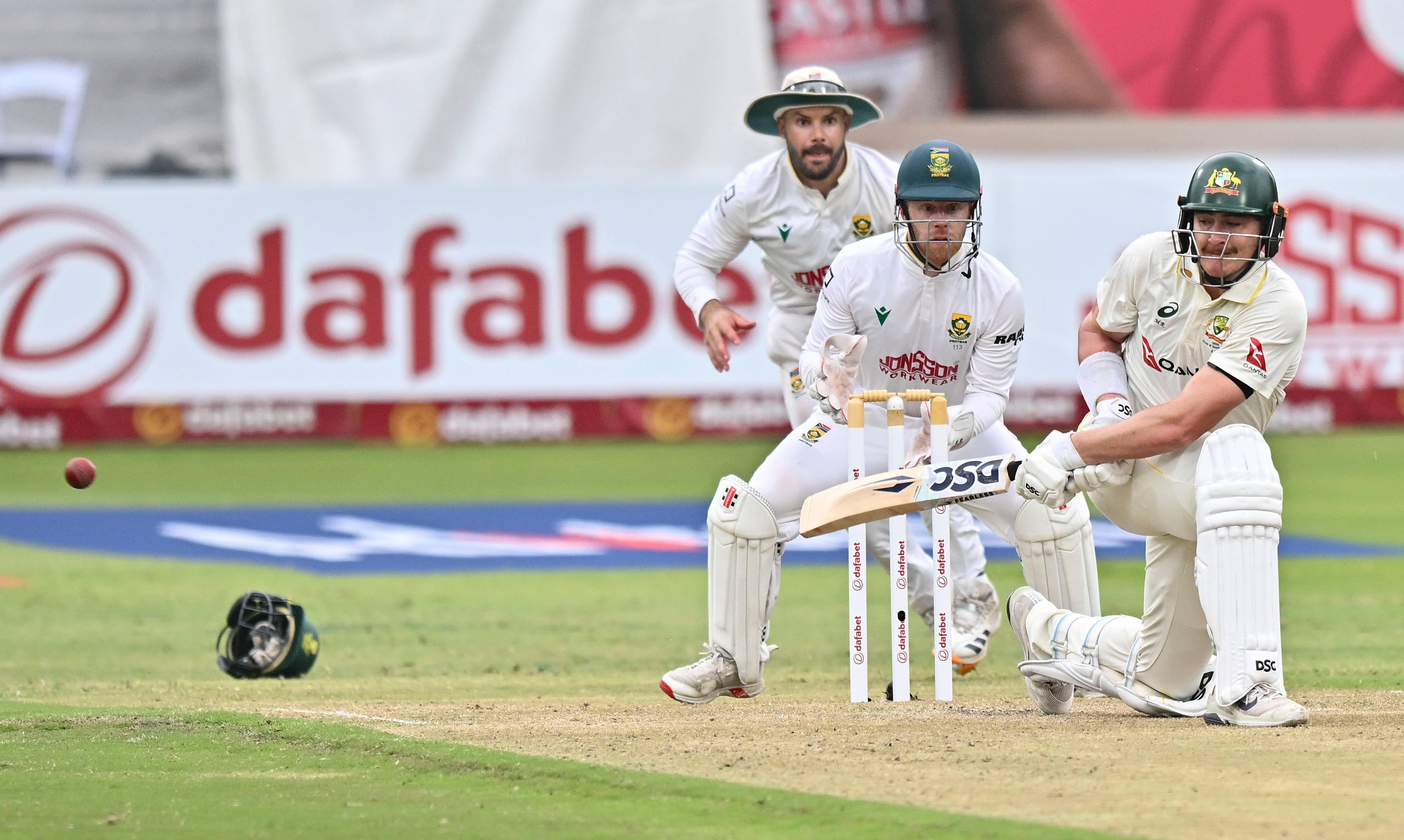 An Australian batter goes on one knee to sweep the ball away to the boundary.