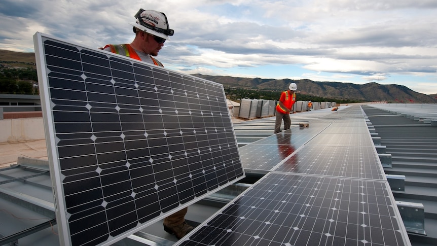 Two workers installing panels on a large scale solar plant. 