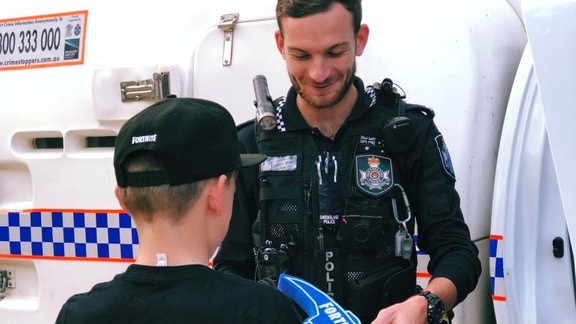 A police officer gives a young boy gaming merchandise