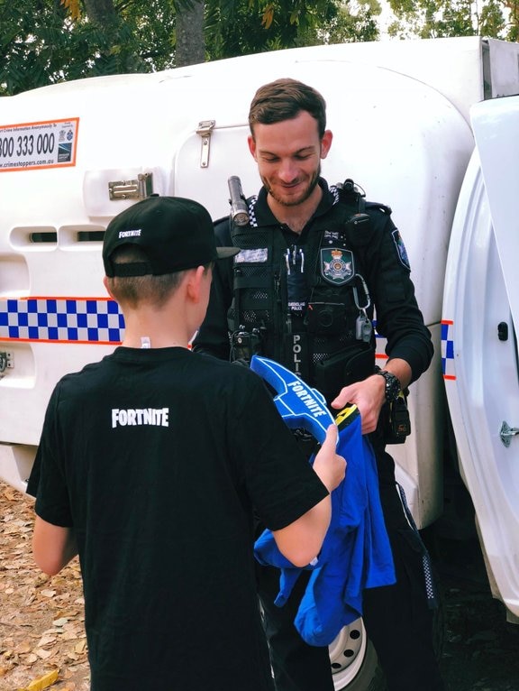 A police officer gives a young boy gaming merchandise