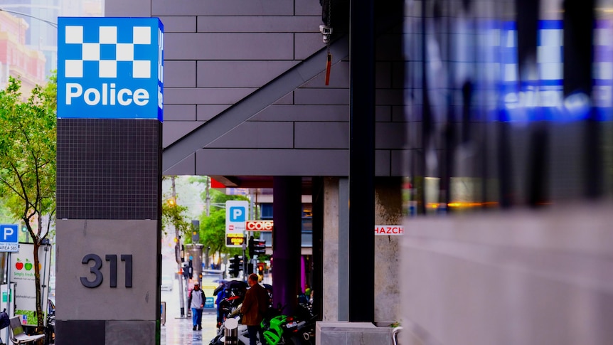 A post with a blue and white police sign on it, next to a CBD footpath.