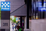 A post with a blue and white police sign on it, next to a CBD footpath.
