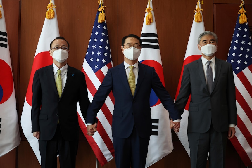 Takehiro Funakoshi、Kim Gun和Sung Kim站在日本、美国和韩国的国旗前