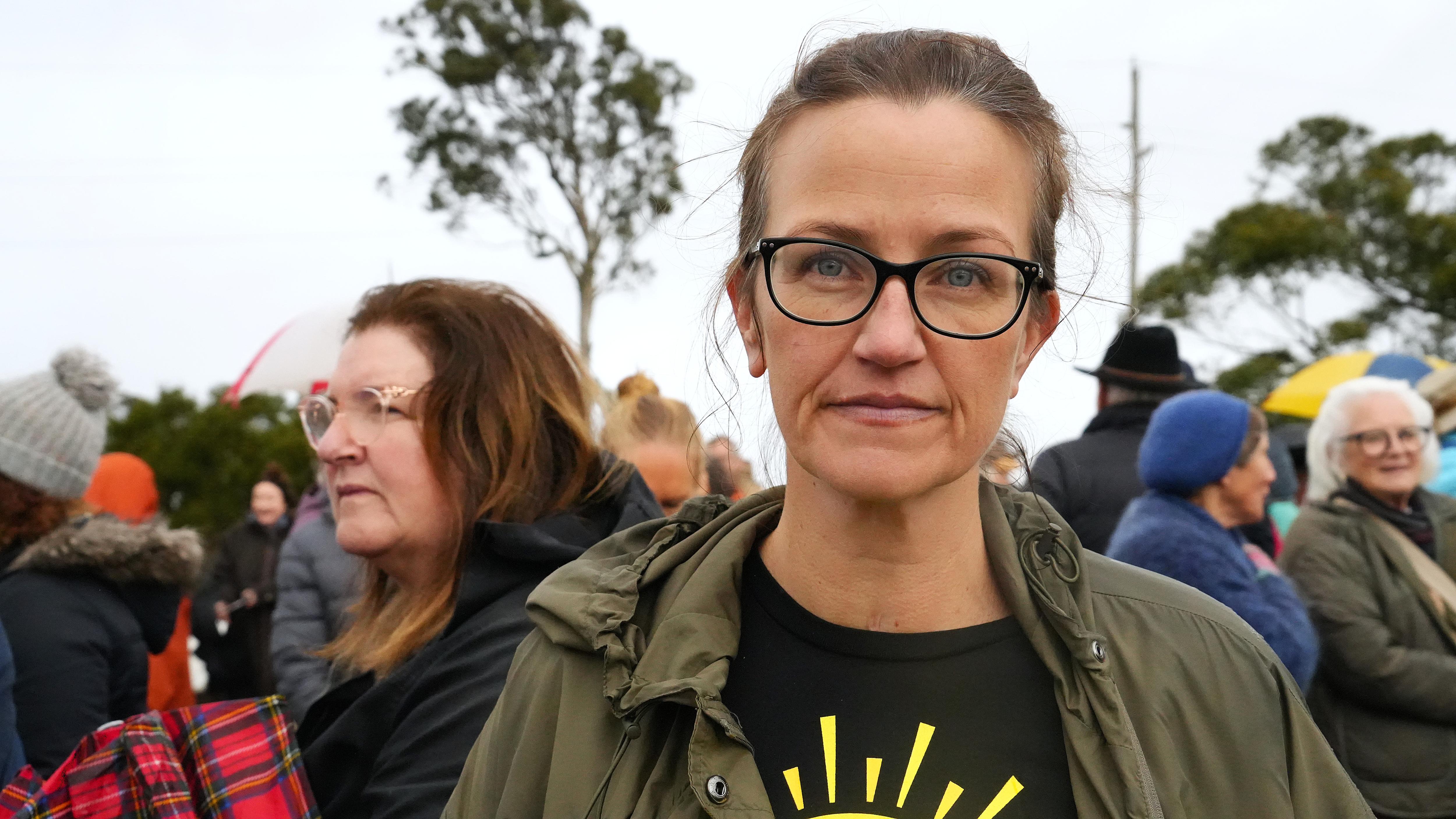weoman in glasses looks at camera in front of a crowd