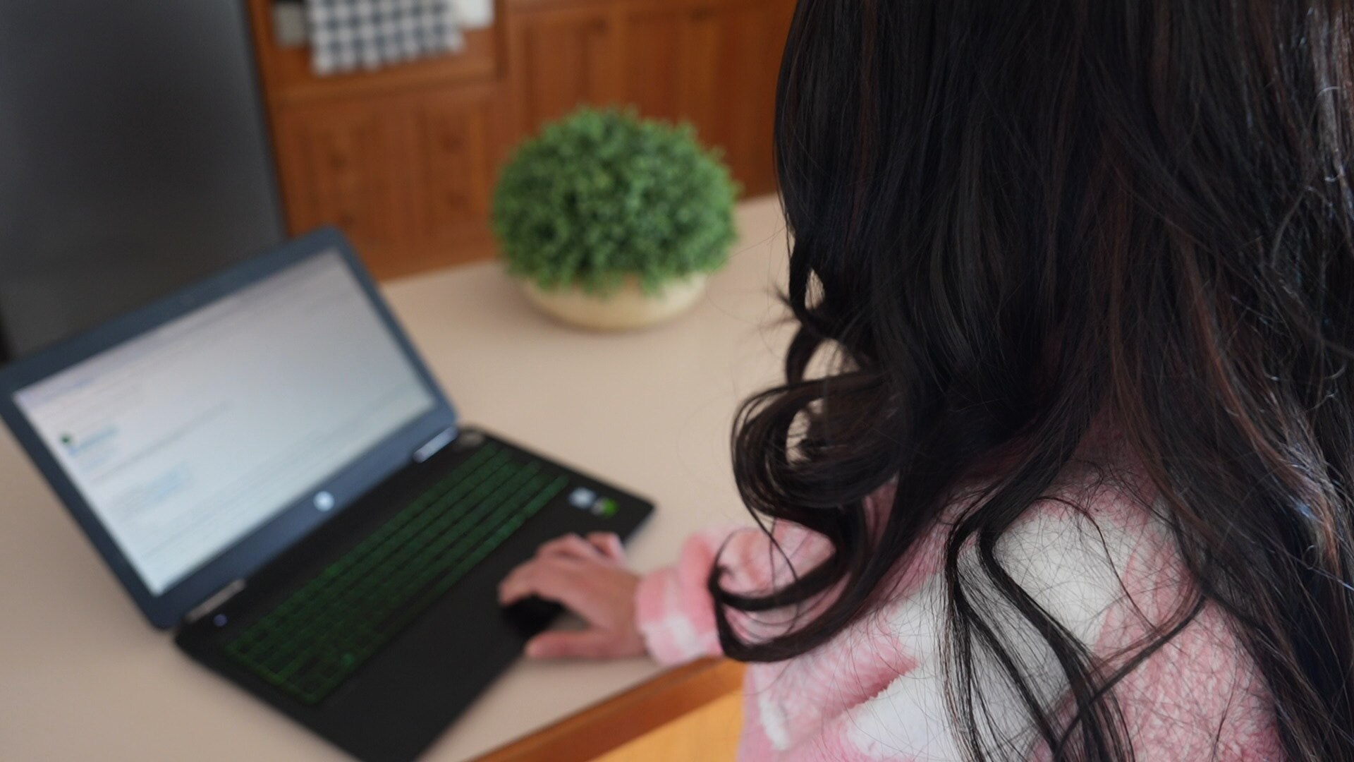 A woman is standing up looking at a laptop. 