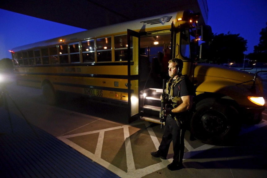 A police officer stands guard at a bus used to evacuate attendees at the Garland Mohammed art exhibit