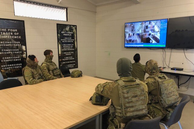 Soldiers watch footage from a military training exercise