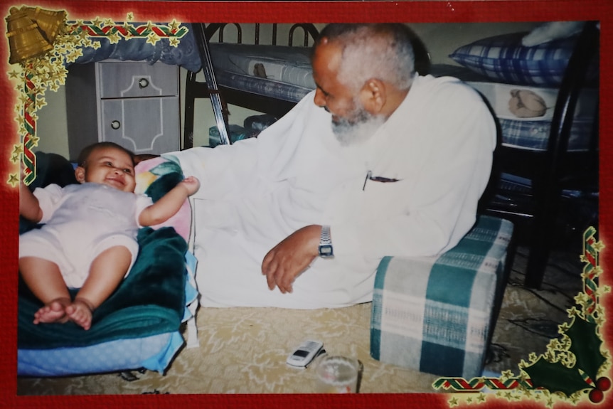 a man sits on the floor looking at a smiling baby boy