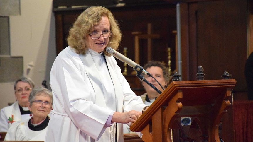 Kimberly Sawyer stands at a microphone to deliver a speech in church at her ordination.