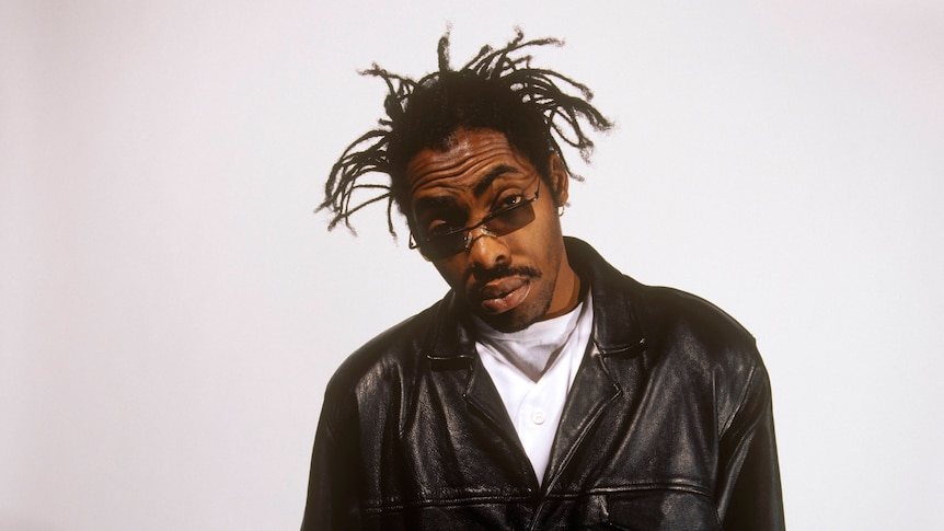 Coolio looks at the camera over a pair of sunglasses while wearing a leather jacket