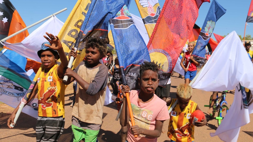 Children march surrounded by enormous colourful flags