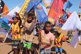 Children march surrounded by enormous colourful flags