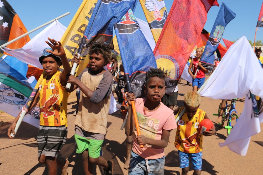 Children march surrounded by enormous colourful flags