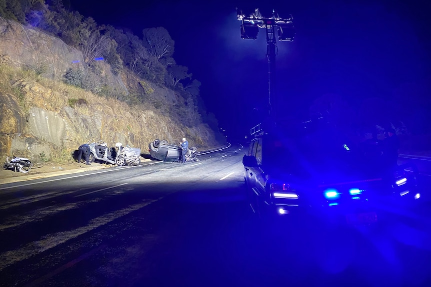 Wreckage of two cars, with police lights illuminating the scene.