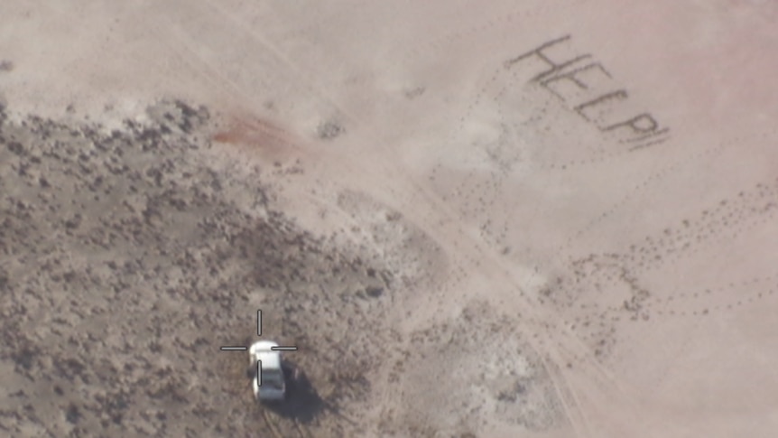 A stranded vehicle and the words HELP written in sand nearby.  