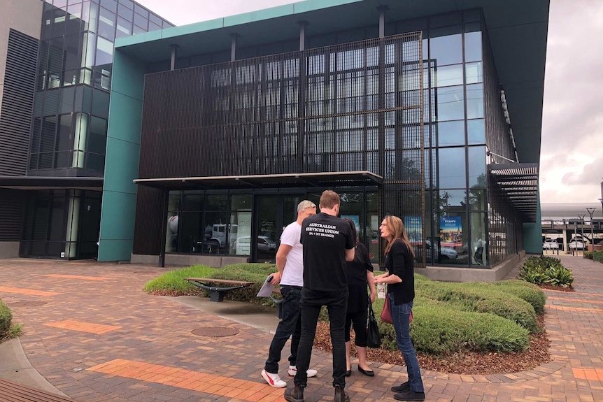 A group of people talk outside a building.