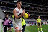 Jack Newnes in a white Carlton jersey holds a yellow sherrin and stares toward the goals